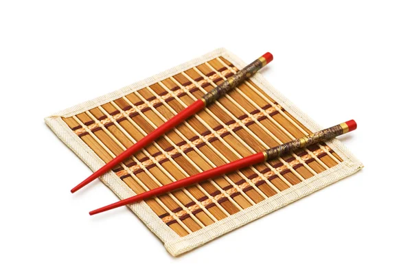 Red chopsticks on the mat isolated on the white — Stock Photo, Image