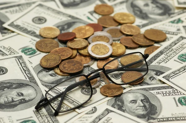 Dólares americanos, vasos de lectura y varias monedas — Foto de Stock