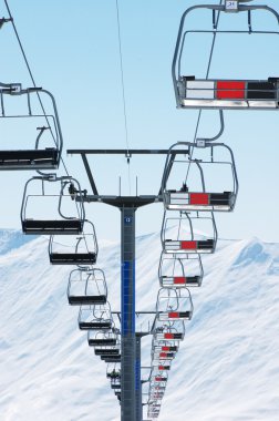 Ski lift chairs on bright winter day clipart