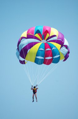 Multi coloured parachute over the blue sky clipart