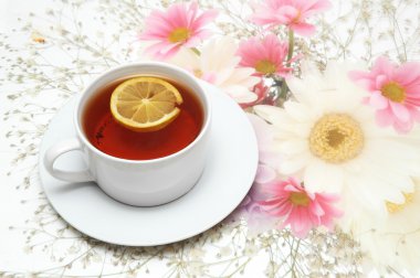 Cup of tea with lemon on flower background clipart