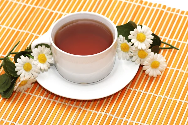 Tasse de thé noir et de camomilles en arrière-plan — Photo