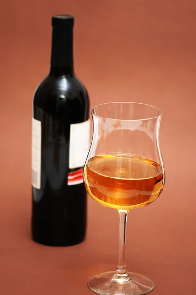 Glas wijn en een fles op biege achtergrond — Stockfoto