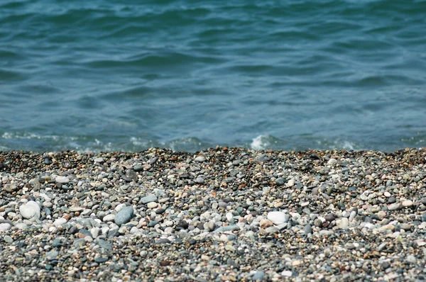 Vatten och små stenar på stranden — Stockfoto