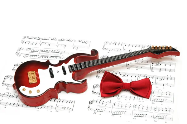 Notas musicales, guitarra y pajarita en blanco — Foto de Stock