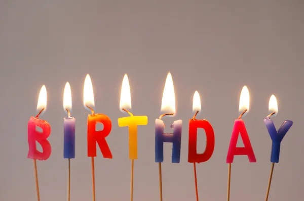 "doğum günü" sözcüğü ile çok renkli mumlar yanan — Stok fotoğraf