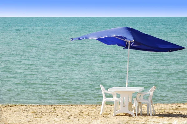 Bord, stolar och parasoll på stranden — Stockfoto