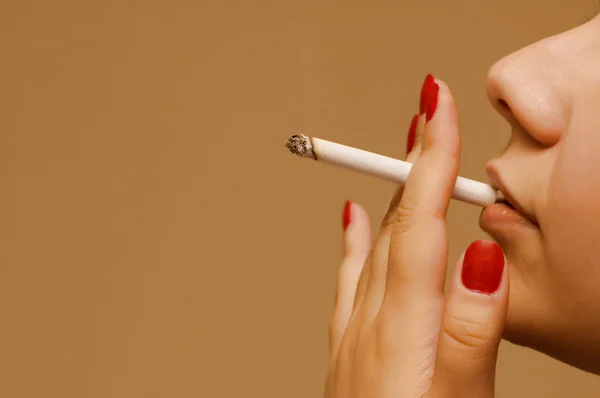 Mulher fumando o cigarro no fundo laranja — Fotografia de Stock