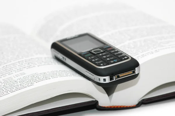 Мобильный телефон над учебником — стоковое фото