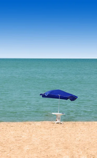 Стол и зонтик на пляже летом — стоковое фото