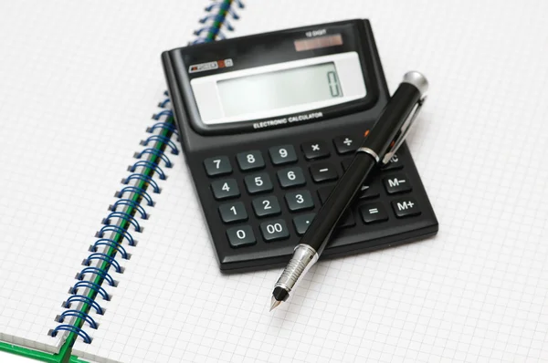 Kalkulator i pióra na kratkę książki — Zdjęcie stockowe
