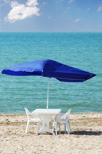 Tavolo, sedie e ombrellone in spiaggia — Foto Stock