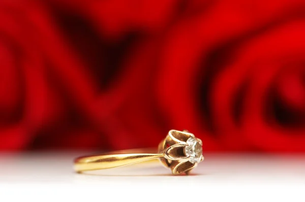 Diamanten ring en rode roos op achtergrond — Stockfoto