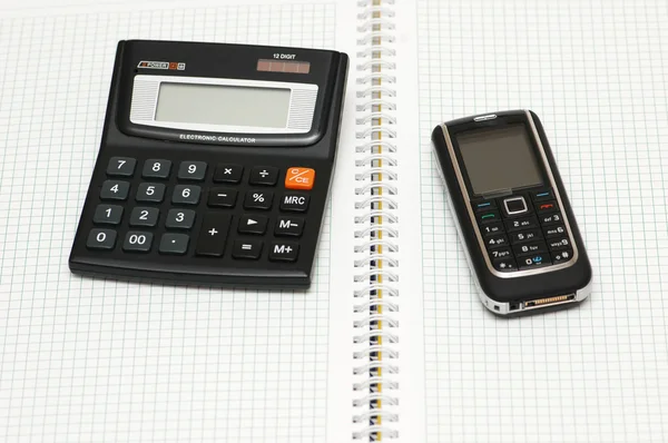 Telefone celular, calculadora e caneta no notebook — Fotografia de Stock