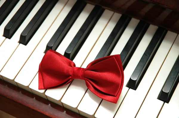 Red bow tie on white piano keys — Stok fotoğraf