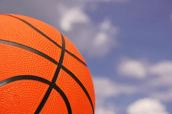 Оранжевый баскетбол на фоне облачного неба — стоковое фото