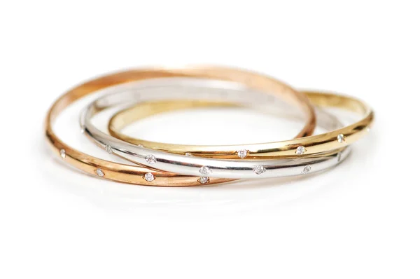 Tre bracciali in oro isolati sul bianco — Foto Stock