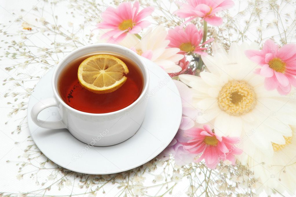 Cup of tea with lemon on flower background
