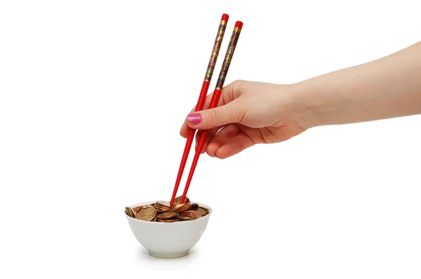 Ruka s červeným hůlkami jíst zlaté mince — Stock fotografie