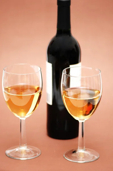 Twee glazen en een fles op biege achtergrond — Stockfoto