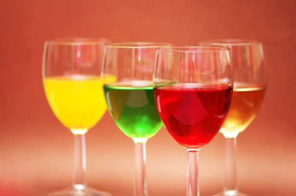 Biege 背景上各种颜色的饮料与眼镜 — 图库照片