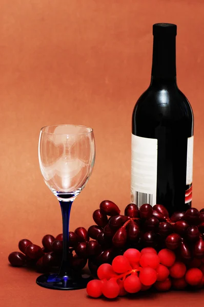 Weinglas, Trauben und Flasche auf biegem Hintergrund — Stockfoto