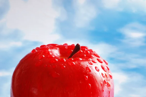 Apfel mit Wassertropfen gegen den blauen Himmel — Stockfoto