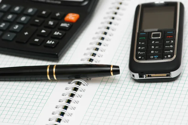 Kalkulator, długopis i telefon komórkowy na notebooka — Zdjęcie stockowe