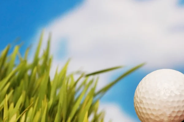 Golfový míček a zelené trávě proti modré obloze — Stock fotografie
