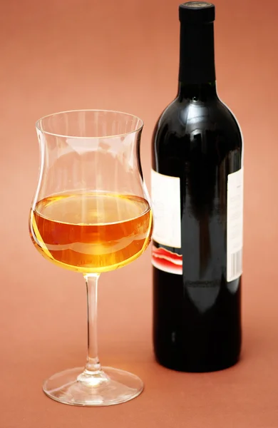 Bicchiere di vino e una bottiglia su sfondo biege — Foto Stock