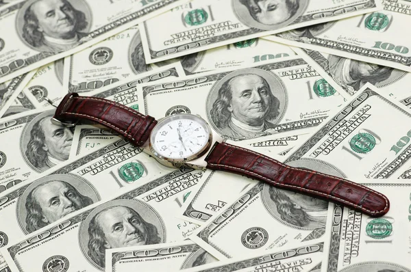 Reloj de mano sobre los billetes de banco de cien dólares — Foto de Stock