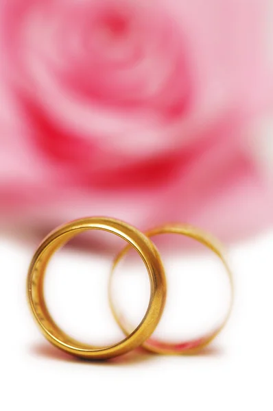 Dois anéis de casamento e rosa rosa no fundo — Fotografia de Stock