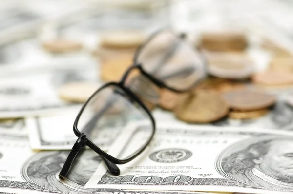 Reading glasses with coins and dollar bank notes — Stock Photo, Image