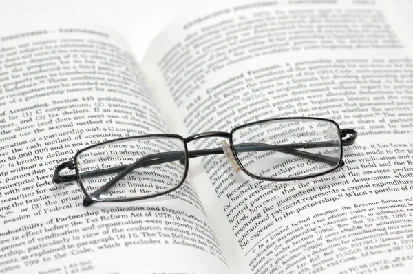Leesbrillen met licht frame over het open boek Rechtenvrije Stockfoto's