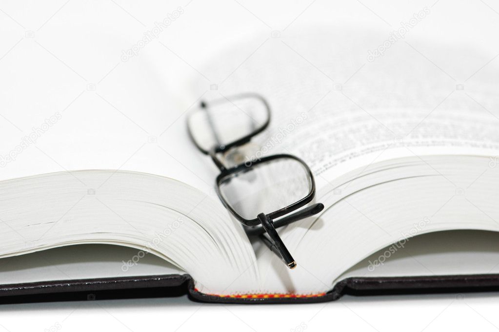 Reading glasses over the open textbook - shallow DOF