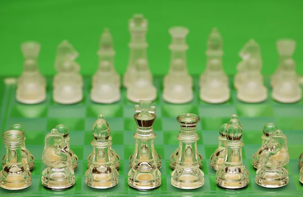 Skleněné šachy postavy před zeleným pozadím — Stock fotografie