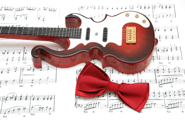Гитара и галстук-бабочка на ноте — стоковое фото