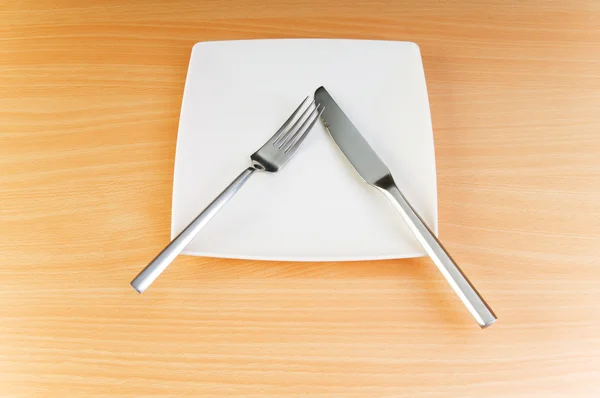 Teller mit Utensilien auf Holztisch — Stockfoto