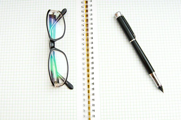 Ручка и очки на странице — стоковое фото