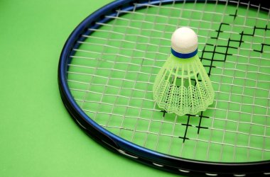 Shuttlecock and racket on green background clipart