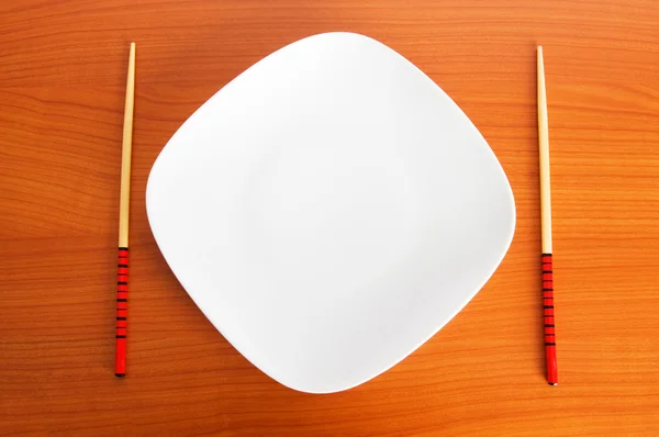 Тарелка с палочками на деревянном столе — стоковое фото