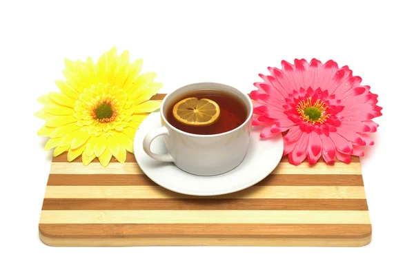 Cup of tea on wooden board and flowers — Stock Photo, Image