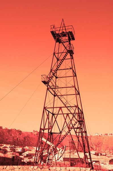 Oil derrick with "donkey" pump during sunset