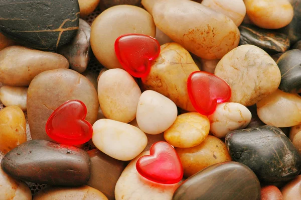 Pebbles no fundo e formas de coração vermelho — Fotografia de Stock