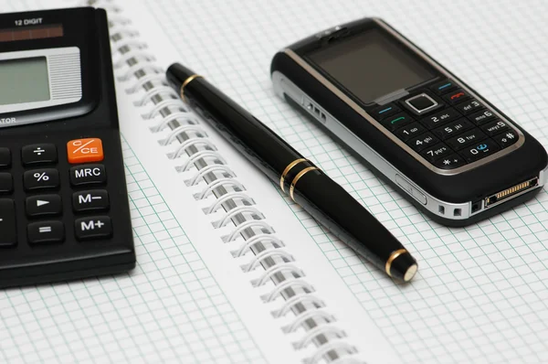 Calculadora, esferográfica e telefone celular no notebook — Fotografia de Stock