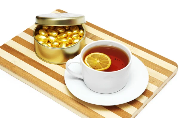 Cup of tea with lemon and chocolates isolated on white — Stock Photo, Image