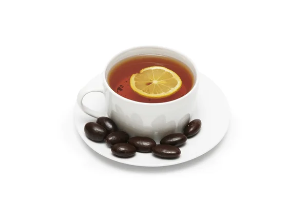 Tazza di tè con limone e cioccolatini isolati su bianco — Foto Stock