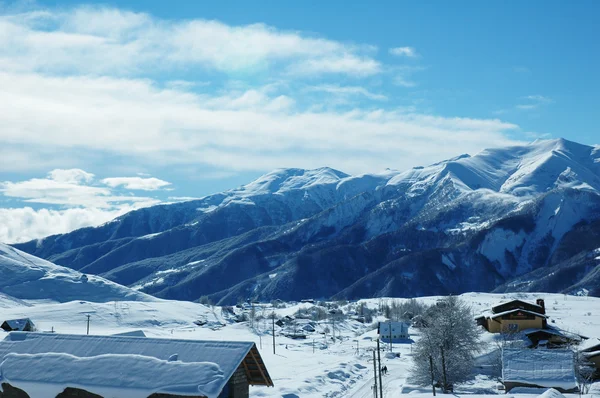 Malé vesnice a hory pokryté sněhem — Stock fotografie