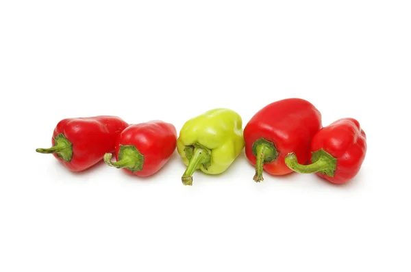 Green Pepper standing out from the crowd of red peppers — Stock Photo, Image