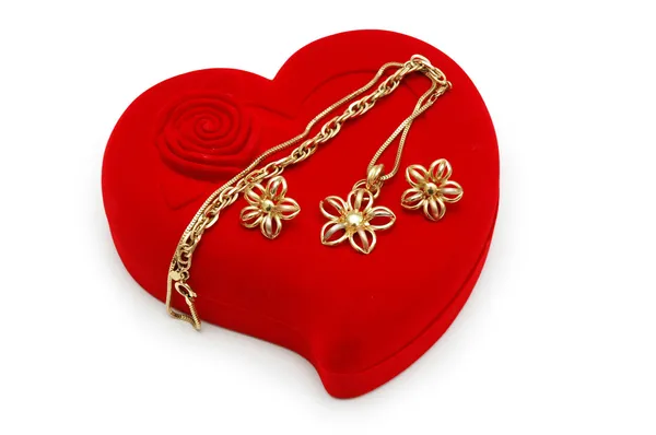 Golden earrings and chain on red heart-shaped box — Stock Photo, Image